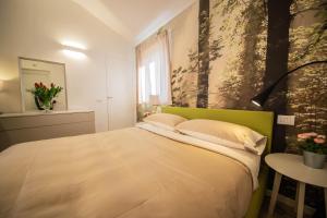 a bedroom with a bed with a green headboard and a table at Gardenhouse Sarzana in Sarzana