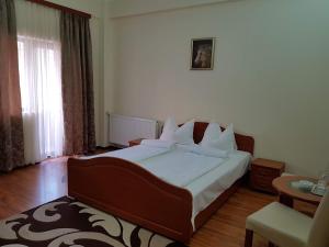 a bedroom with a large bed with white sheets and pillows at Vila Orhidee in Eforie Nord +1 photo