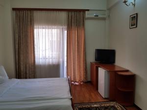 a bedroom with a bed and a tv and a window at Vila Orhidee in Eforie Nord