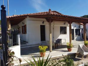 une petite maison blanche avec une pergola en bois dans l'établissement G-George Apartments by the Sea and Airport, à Liádha