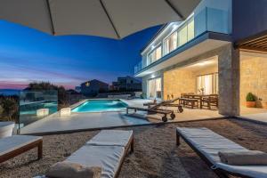 a house with a swimming pool in the backyard at Villa Olea, luxury retreat with nature blend in Novalja