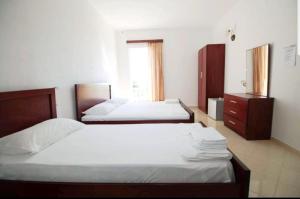 a bedroom with two beds and a dresser and a window at Hotel Afrodite in Dhërmi
