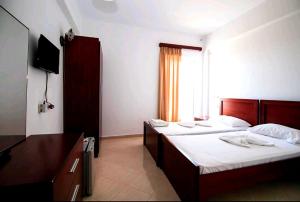 a hotel room with two beds and a television at Hotel Afrodite in Dhërmi