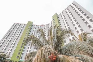 a tall building with palm trees in front of it at OYO 498 Green Lake View Ciputat in Pondokcabe Hilir