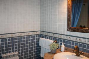 W wyłożonej niebieskimi kafelkami łazience znajduje się umywalka i lustro. w obiekcie Apartamentos Rurales Rosendo: La Madre Selva w mieście Capileira +6 zdjęć