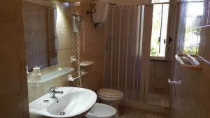 Un baño con lavabo, inodoro y ventana. en Casa Giusy, en Capo Vaticano