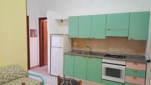 Una cocina con gabinetes verdes y un refrigerador blanco. en Casa Giusy, en Capo Vaticano 53 fotos más