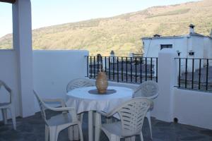 a white table with chairs and a vase on a balcony at Apartamentos Rurales Rosendo: La Albahaca in Capileira