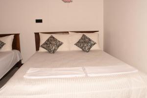 a bed with white sheets and pillows in a room at Sea Zone Hotel Nilaveli in Nilaveli