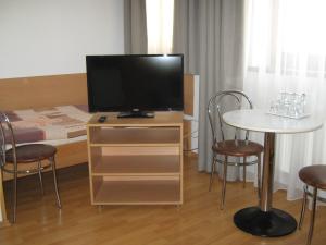 Habitación con TV y mesa con sillas. en Penzion U Radnice en Kyjov