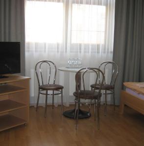 Habitación con 3 sillas, mesa y TV. en Penzion U Radnice en Kyjov