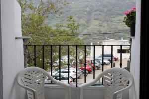 einen Balkon mit 2 Stühlen und Blick auf einen Parkplatz in der Unterkunft Apartamentos Rurales Rosendo: El Azahar in Capileira