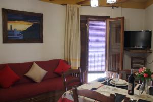 een woonkamer met een rode bank en een tafel bij Apartamentos Rurales Rosendo: El Azahar in Capileira