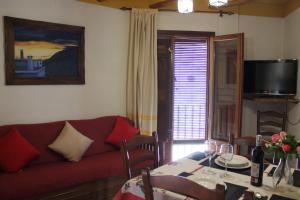 a living room with a red couch and a table at Apartamentos Rurales Rosendo: El Azahar in Capileira