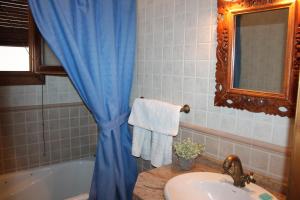 a bathroom with a blue shower curtain and a sink at Apartamentos Rurales Rosendo: El Azahar in Capileira +4 photos