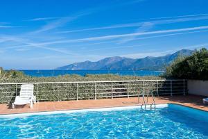 una piscina con una silla y vistas al océano en Studio A Suarella, en Saint-Florent