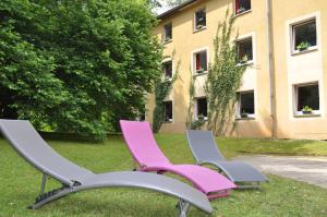 three chairs sitting in the grass in front of a building at Enzo Hôtels Premier Prix - Logis Amnéville in Amnéville