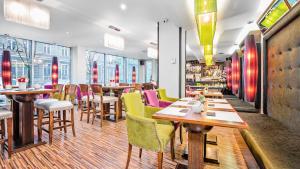 un restaurante con mesas de madera y sillas coloridas en Don Prestige Residence, en Poznan