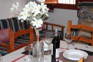 een tafel met een fles wijn en een vaas met bloemen bij Apartamentos Rurales Rosendo: El Romero in Capileira