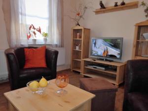 ein Wohnzimmer mit einem TV und einem Tisch in der Unterkunft Ferienhaus Alte Tante in Thale