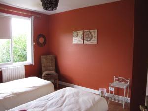 Schlafzimmer mit orangefarbenen Wänden, 2 Betten und einem Fenster in der Unterkunft Gîte "Au Gré de l'Adour" in Aire-sur-lʼAdour