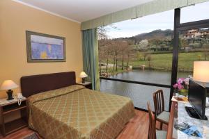 ein Schlafzimmer mit einem Bett und einem großen Fenster in der Unterkunft Hotel Lago Verde in Serravalle Pistoiese