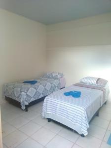 - deux lits assis l'un à côté de l'autre dans une pièce dans l'établissement Hostel Pigally, à Goiânia