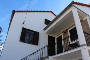 ein weißes Haus mit schwarzen Fenstern und einem Balkon in der Unterkunft Marquinhas House - A Queijeira in Oliveira do Hospital