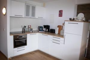 a white kitchen with white cabinets and a sink at Welcome in - Wohnung mit Dachterrasse direkt an der Piste in Winterberg