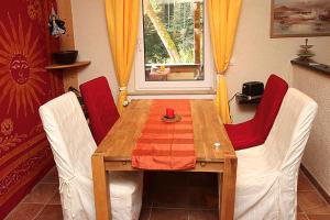stół jadalny z 2 krzesłami i stół z czerwoną tkaniną w obiekcie Ferienwohnungen im Harz w mieście Altenbrak