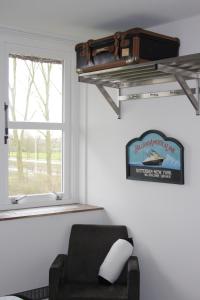 a living room with a chair and a suitcase on a shelf at B&B Pension "Op'e Koai" in Jirnsum