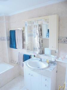 a white bathroom with a sink and a tub and a mirror at Pancho Apartment Doña Pepa - C. Quesada in Rojales