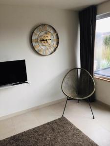 um quarto com um relógio na parede e uma cadeira em Les terrasses de Malmédy em Malmedy