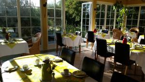 un comedor con mesas, sillas y ventanas en Hotel Villa Magnolia, en Rödermark