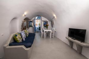 Una sala de estar con un sofá y un televisor. en Santo Blue Horizon Blue domes view, en Oia
