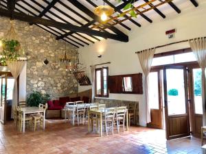 ein Wohnzimmer mit Tischen und Stühlen und einer Steinmauer in der Unterkunft Agriturismo Ristorante Monte Argentario in Monte Argentario