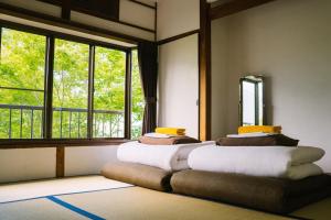 a room with two beds in front of a window at Onsen Guesthouse HAKONE TENT in Hakone