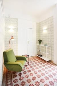 a living room with a green chair and a carpet at Le Quinte del Bellini in Naples