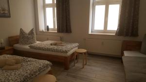 a room with two beds and a couch and two windows at Fewo Am Marktplatz I in Eisenhüttenstadt