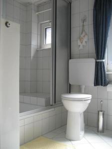 ein weißes Bad mit einem WC und einer Dusche in der Unterkunft Ferienhaus "Antje" in Bad Zwischenahn