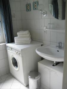 ein weißes Badezimmer mit einer Waschmaschine und einem Waschbecken in der Unterkunft Ferienhaus "Antje" in Bad Zwischenahn