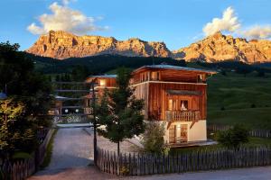 a house with a fence in front of a mountain at Appartamenti La Sajun & Les Viles in La Villa