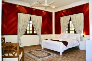 a bedroom with a white bed and red walls at Astana Az-Zahrah in Bahau