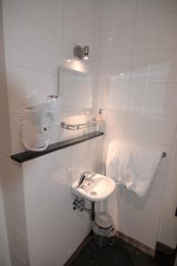 a white bathroom with a sink and a toilet at Hotel Bienvenue in Rotterdam