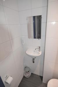 Baño blanco con lavabo y espejo en Hotel Bienvenue, en Róterdam