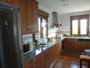 a large kitchen with wooden cabinets and a microwave at CHALT EN MIÑO CON VISTAS AL MAR in A Coruña +22 photos