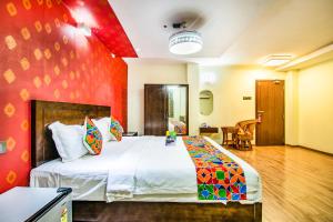 a bedroom with a large bed with a red wall at FabHotel Prince Park Vellore in Vellore