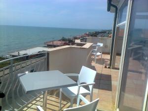 un balcón con sillas blancas, una mesa y el océano en Hotel L'Approdo, en Anzio