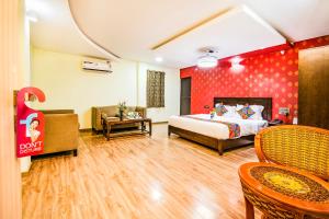 a hotel room with a bed and a couch and chairs at FabHotel Prince Park Vellore in Vellore