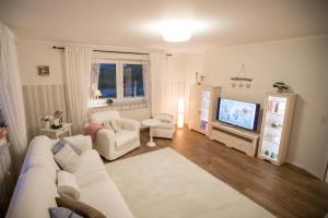 a living room with a white couch and a tv at Landhaus in Swisttal